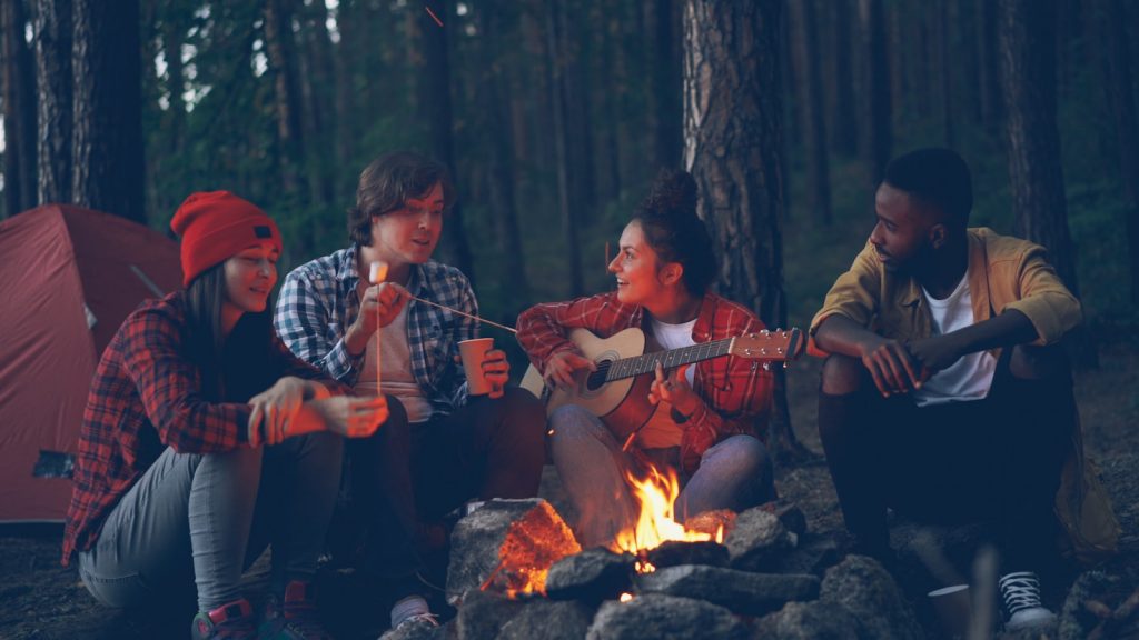Friends gathered around a campfire at night